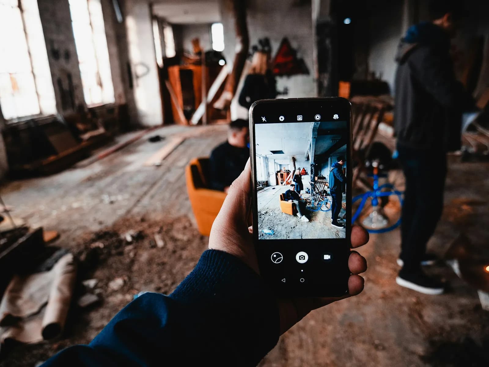 A phone held up to photograph a renovation in progress, the room and the crew on its screen